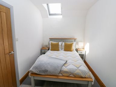 A bedroom with a bed with cushions and bedside tables with lamps at 3 The Barn in Haverfordwest