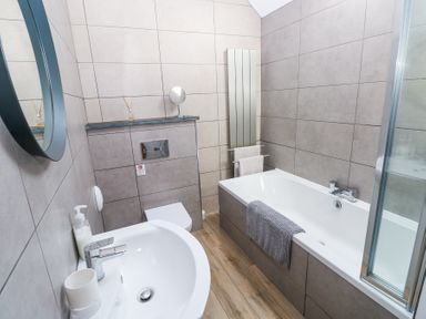 A bathroom with a sink a toilet a bathtub with a towel and a mirror on the wall at 3 The Barn in Haverfordwest