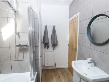 A bathroom with a shower bathtub sink mirror wooden door and two towels hanging at 3 The Barn in Haverfordwest