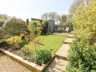 A garden with a lawn patio seating area small shed and various plants at 3 The Barn in Haverfordwest