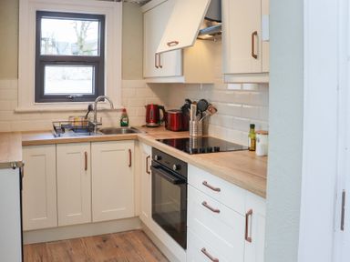 A kitchen with a window, sink, stove, oven, countertop appliances, and white cabinets at Heatherbell House Ballyhoura near Buttevant