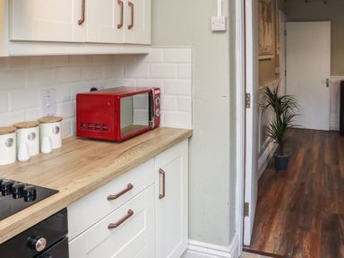 A kitchen corner with a red microwave on a wooden countertop and white cabinets at Heatherbell House Ballyhoura near Buttevant