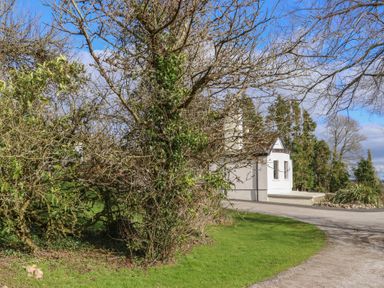 A driveway with a curved path leading to a white house partly obscured by leafless trees at Heatherbell House Ballyhoura near Buttevant