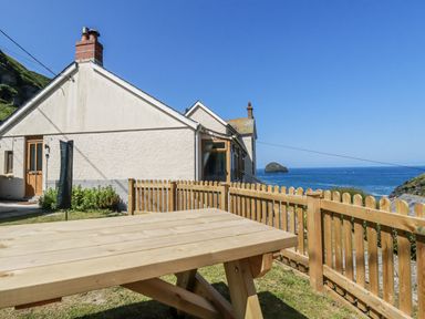 An outdoor area with a table and a view of the ocean at Lazy Days in St Merryn