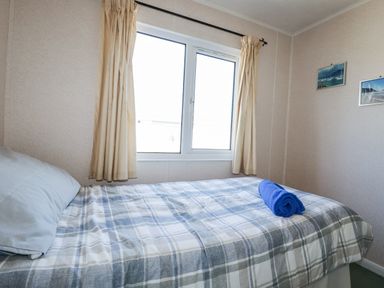 A bedroom with a bed and a window at Lazy Days in St Merryn