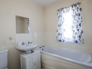 A bathroom with a bathtub, sink and toilet at Lazy Days in St Merryn