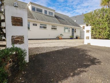 Exterior view of a white house with gravel driveway and potted plants at Coastmans Nest in Mawgan Porth