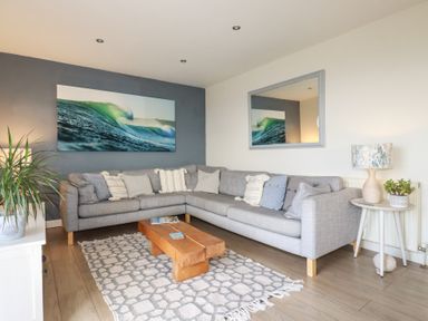 A living room with a gray sectional sofa and wooden coffee table at Coastmans Nest in Mawgan Porth