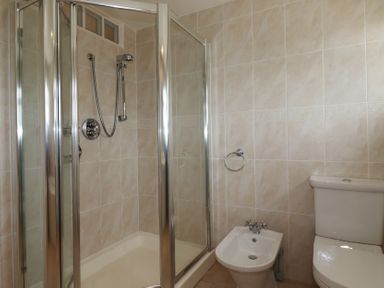 A bathroom with a glass shower enclosure a bidet and a toilet at Coastmans Nest in Mawgan Porth