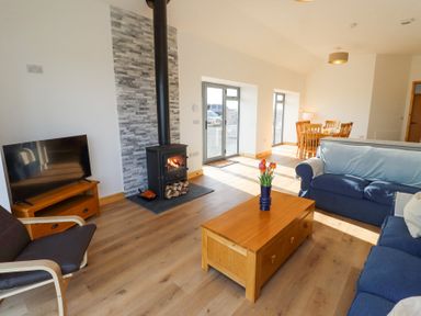 A living room with a wood burning stove TV wooden coffee table and blue sofas at West Burton Hemmel in Bamburgh