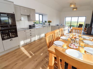 A kitchen and dining area with a wooden table set with plates and glasses of orange juice at West Burton Hemmel in Bamburgh