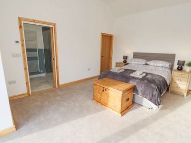 A bedroom with a double bed two bedside tables lamps and a wooden chest at West Burton Hemmel in Bamburgh