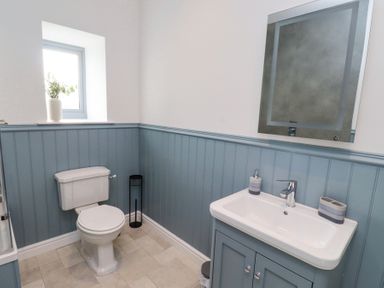 A bathroom with a toilet and a sink with a mirror above at West Burton Hemmel in Bamburgh
