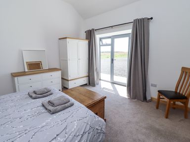 A bedroom with a bed and white furniture at West Burton Hemmel in Bamburgh