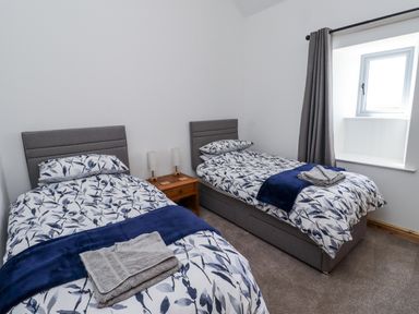 A bedroom with two single beds and a window at West Burton Hemmel in Bamburgh