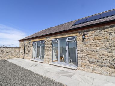 An outdoor area with stone walls and windows at West Burton Hemmel in Bamburgh