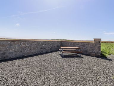 An outdoor area with a picnic table and a stone wall at West Burton Hemmel Bamburgh