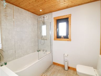 A bathroom with a bathtub shower combination window and toilet at Alpaca Lodge in Barkston