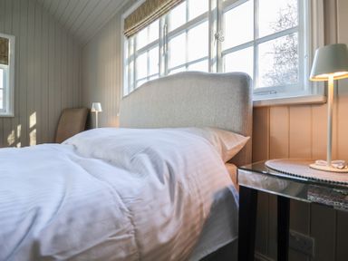 A bedroom with a bed a side table with lamp and windows at The Woodshed in Tendring near Weeley