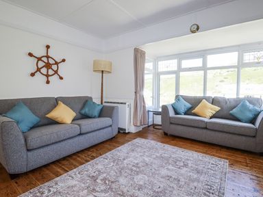 A living room with two sofas and a decorative wall piece at Sea Ledge in Tintagel
