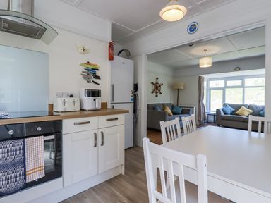 A kitchen with appliances and a dining table at Sea Ledge in Tintagel