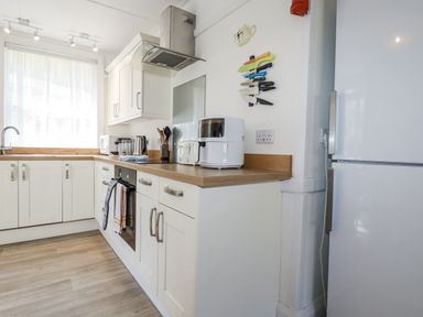 A kitchen with cabinets, sink, and refrigerator at Sea Ledge Tintagel