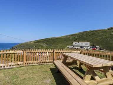 An outdoor area with a wooden table and fence at Sea Ledge in Tintagel