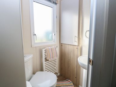 A small bathroom with a toilet sink towel radiator and window at Breathing Space Happisburgh near Walcott