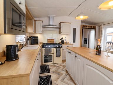 A kitchen with a microwave oven gas stove double door refrigerator wooden countertops and cabinets at Lodge 36 Kingfisher Lodge Wickhamford near Evesham