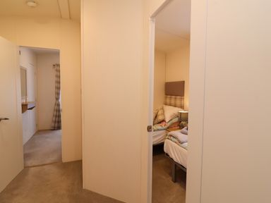 A hallway leading to a room with a bed and a lamp at Lodge 36 - Kingfisher Lodge in Wickhamford near Evesham