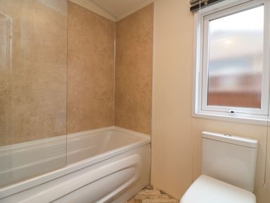 A bathroom with a white bathtub and a toilet next to a window at Lodge 36 - Kingfisher Lodge in Wickhamford near Evesham