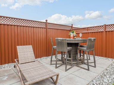 A patio with a wicker lounge chair a round wicker table and four wicker chairs with drinks on the table at Lodge 36 - Kingfisher Lodge in Wickhamford near Evesham