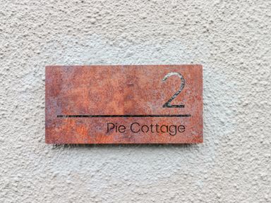 A house number plaque with number 2 and text Pie Cottage on a textured wall at Pie Cottage in Teignmouth