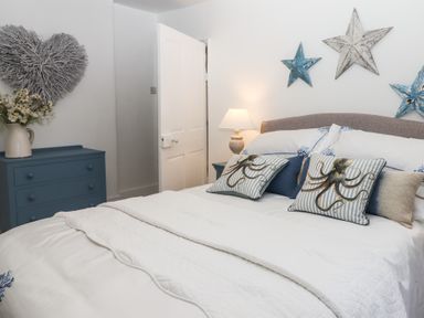 A bedroom with a bed with octopus cushions a blue chest of drawers and star wall decorations at Pie Cottage in Teignmouth