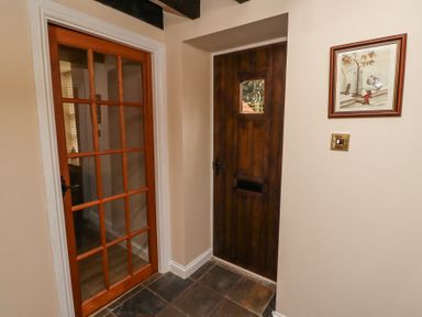 A hallway with a wooden door and a glass-paneled door with a framed picture on the wall at Timberwick Green Akeld near Wooler