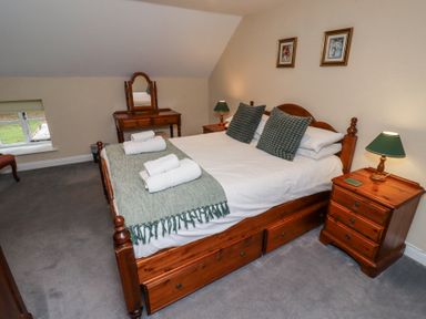A bedroom with a wooden bed and side tables with lamps at Timberwick Green in Akeld near Wooler