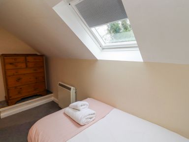 A bedroom with a bed with folded towels on it a wooden chest of drawers and a skylight window at Timberwick Green in Akeld near Wooler