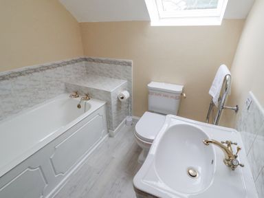 A bathroom with a bathtub toilet sink and towel rack under a skylight at Timberwick Green in Akeld near Wooler