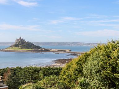 A coastal view with a castle on an island and trees in the foreground at Sea View Loft in Rosudgeon