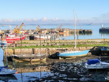 A harbor with several docked boats and fishing vessels near stone walls at Sea View Loft in Rosudgeon