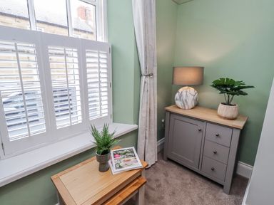 A corner with a cabinet, lamp, plant, and magazine at 3 Lisburn Street Alnwick