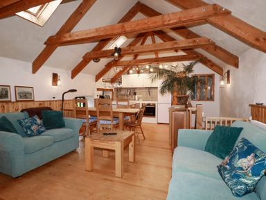 A living room with a sofa and dining table at Stribleys Barn in Cusgarne near St Day