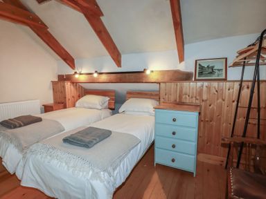 A bedroom with twin beds and wooden furniture at Stribleys Barn in Cusgarne near St Day