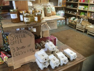 A display of honey, egg cartons, and dry goods in a store at Stribleys Barn in Cusgarne