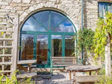 A garden area with arched doors and outdoor seating at Stribleys Barn, Cusgarne, Truro