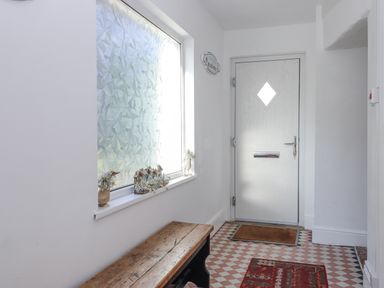 A hallway with a bench and a decorative window at Delmonte Lodge in Torquay