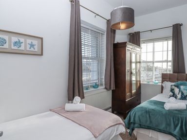 A bedroom with two beds and a wardrobe at Delmonte Lodge in Torquay