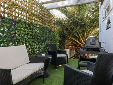 An outdoor seating area with a grill and palm tree at Delmonte Lodge in Torquay