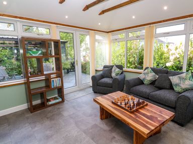 A living room with gray sofas and a wooden coffee table with a chess set at Little Acorns in Gweek