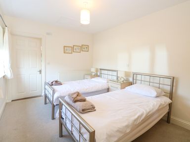 A bedroom with two single beds with white bedding and towels on each bed at Swallow Barn in Holton near Halesworth